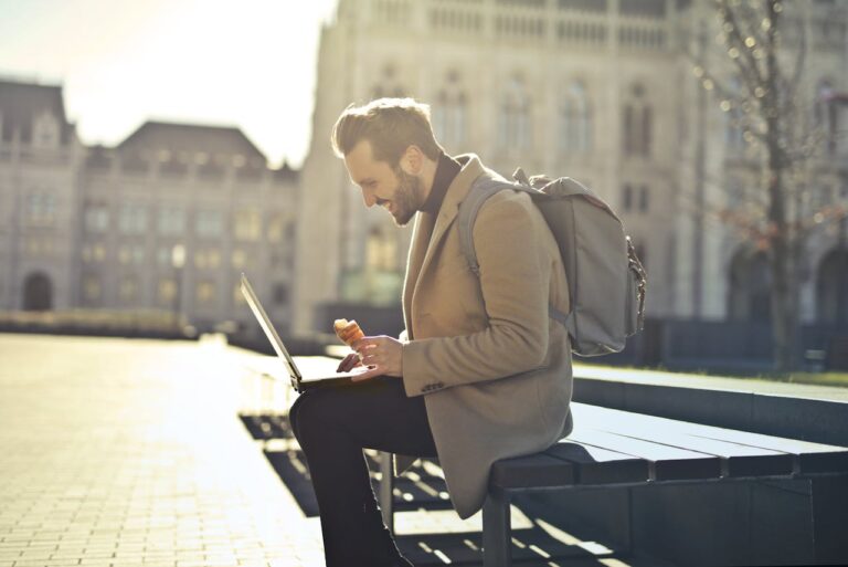 A digital nomad men working next to the Hungarian Parliament on a bench