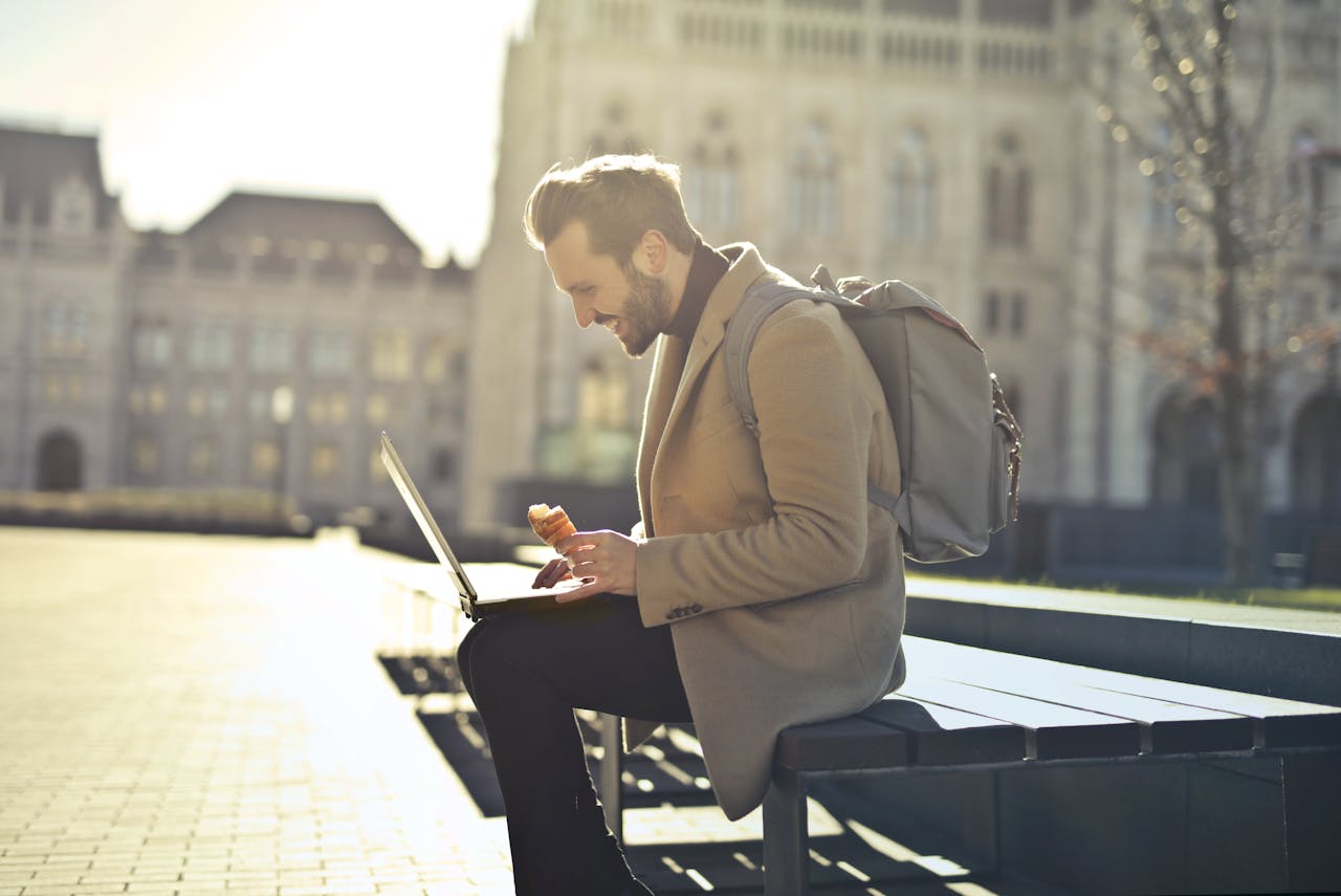 A digital nomad men working next to the Hungarian Parliament on a bench