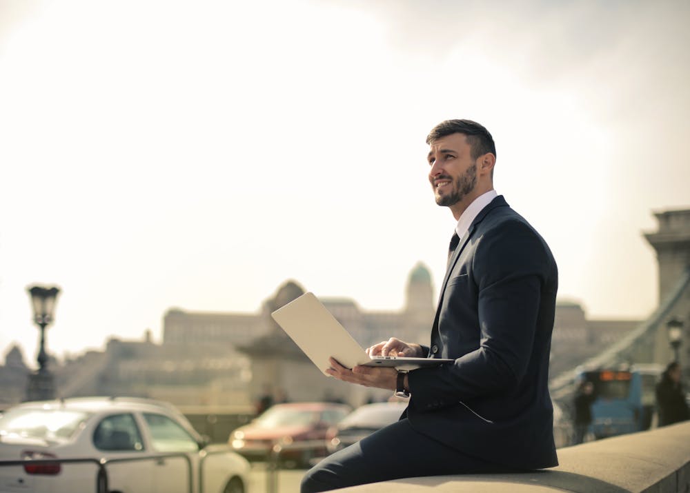 A man working with a laptop while sitting on the Chain Bridge in Budapest, Hungary.